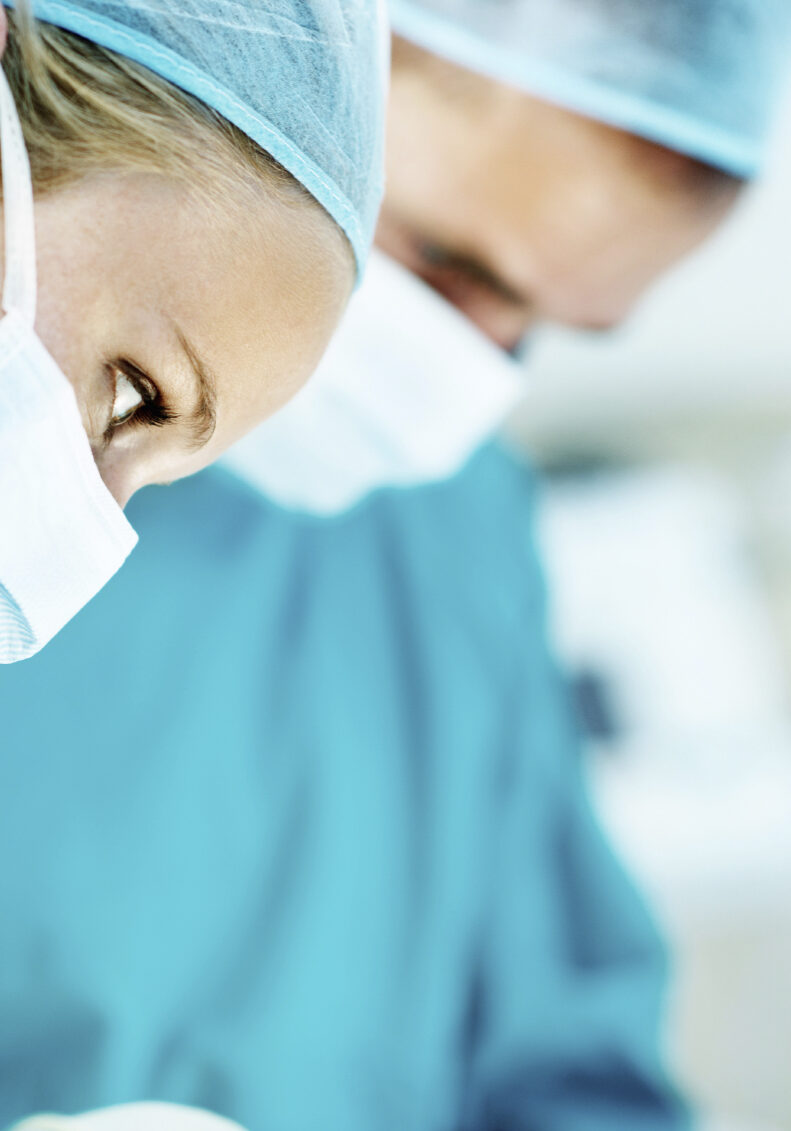 Profile shot of surgeons working together while wearing operating room scrubs